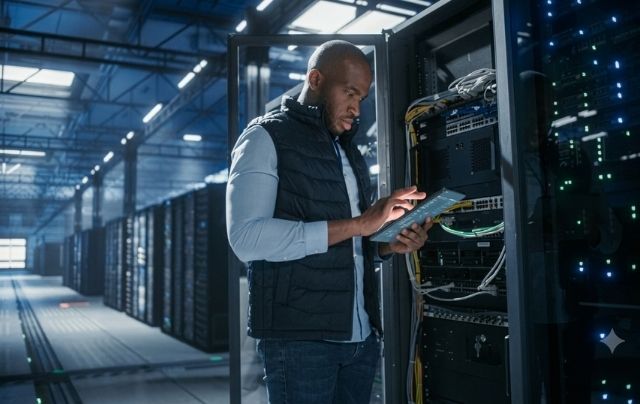 Technician inspecting network equipment in a server rack for DAS antenna system planning