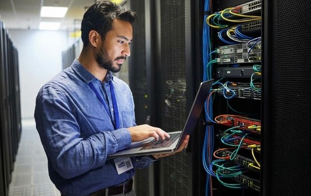 DAS System Design technician inspecting server rack cabling connections.