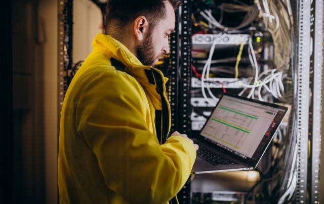 Engineer inspecting cabling in a hospital server rack for phased in-building DAS installation